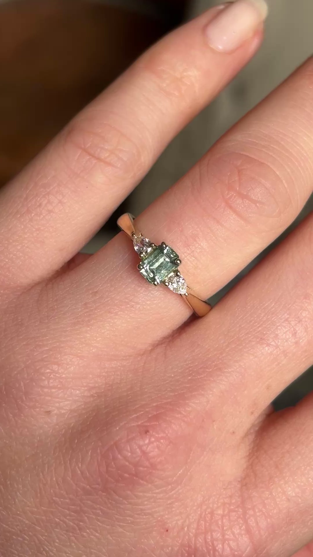 Video of a green sapphire and diamond three-stone engagement ring worn on the hand, showing sparkle and colour in motion.