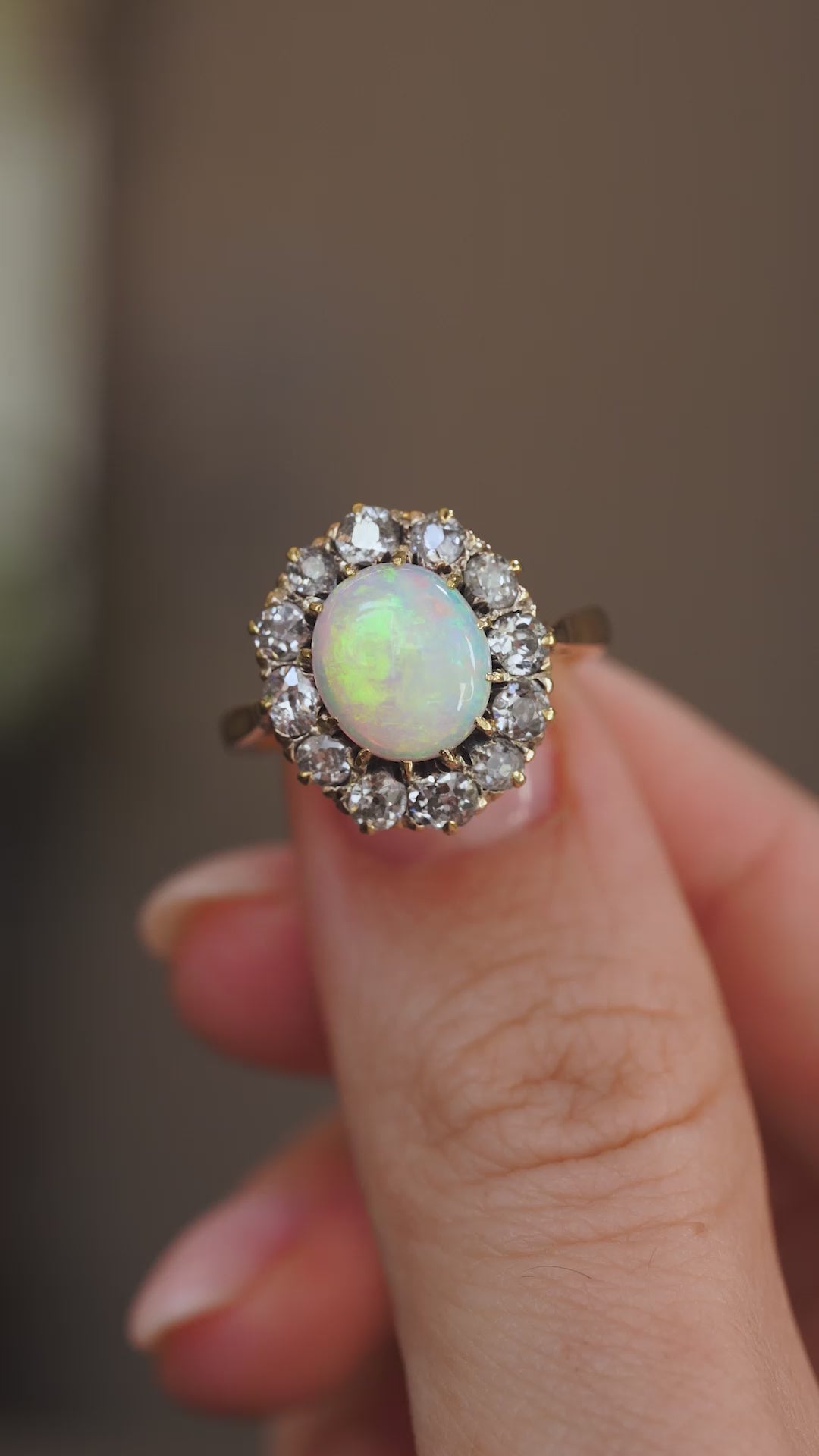 Video close-up presenting the Edwardian opal and diamond cluster ring balanced on a fingertip.