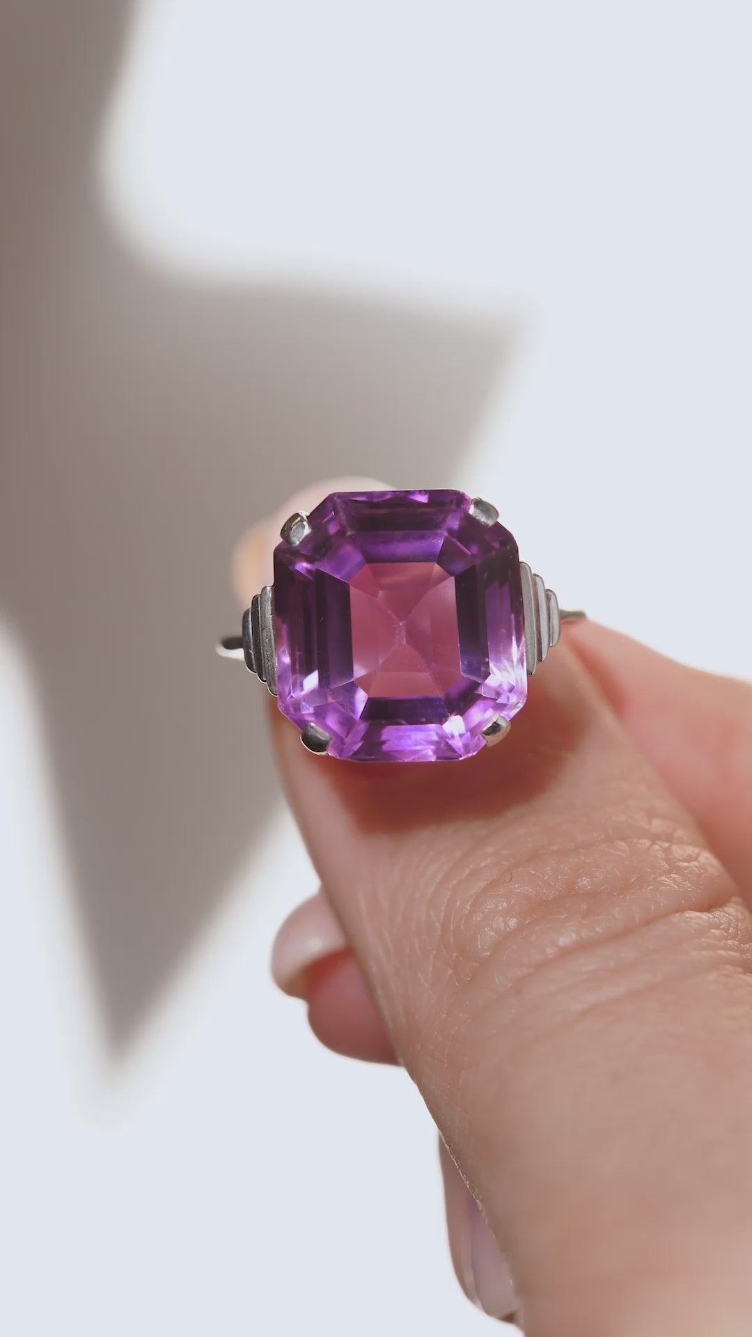 A close-up video of the amethyst cocktail ring held between fingers, highlighting the gemstone's rich violet colour and reflective facets.