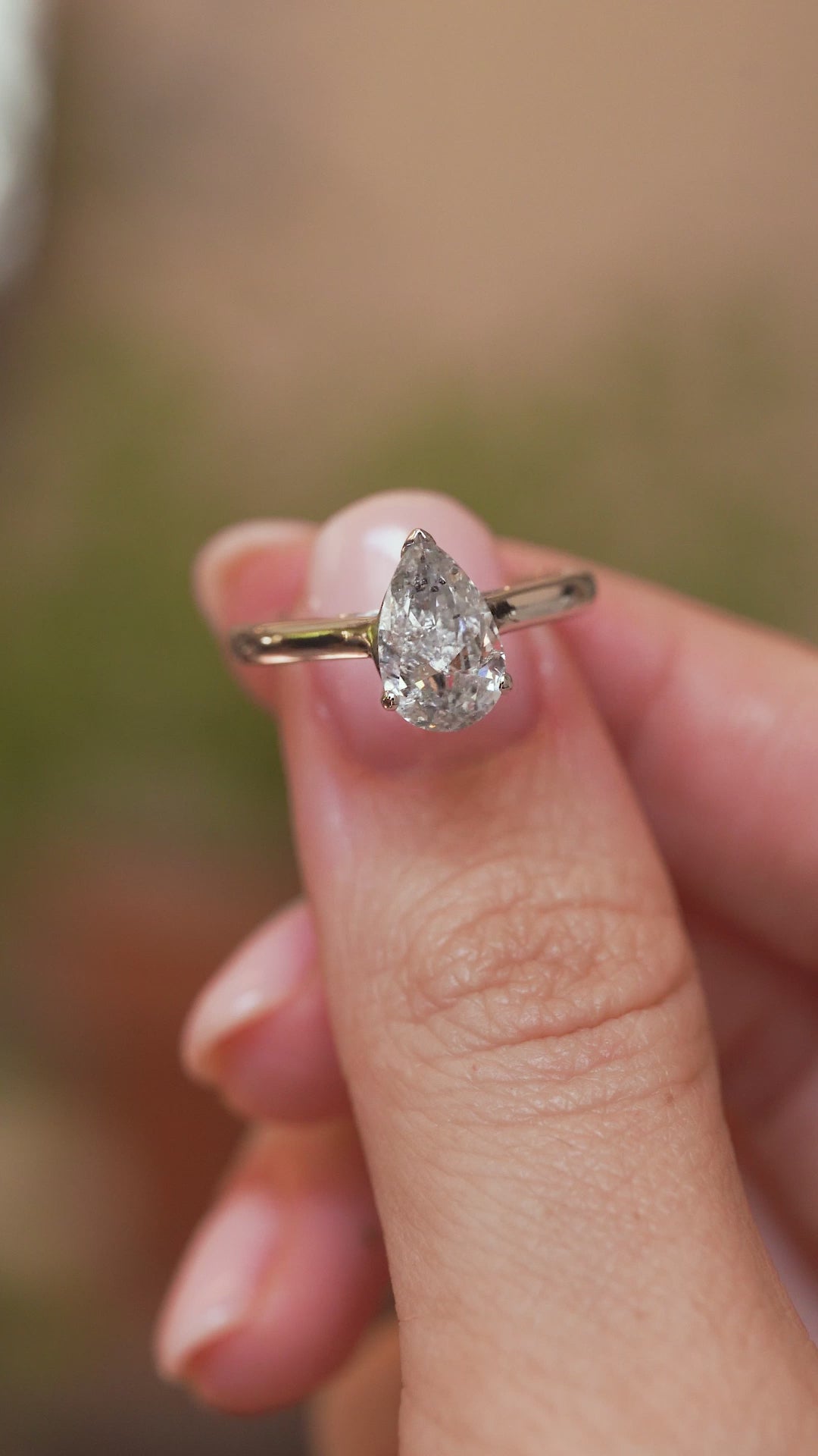 Video close-up of a vintage salt and pepper diamond ring balanced on a fingertip, displaying the pear cut and minimalist white gold design.