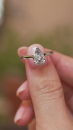 Video close-up of a vintage salt and pepper diamond ring balanced on a fingertip, displaying the pear cut and minimalist white gold design.