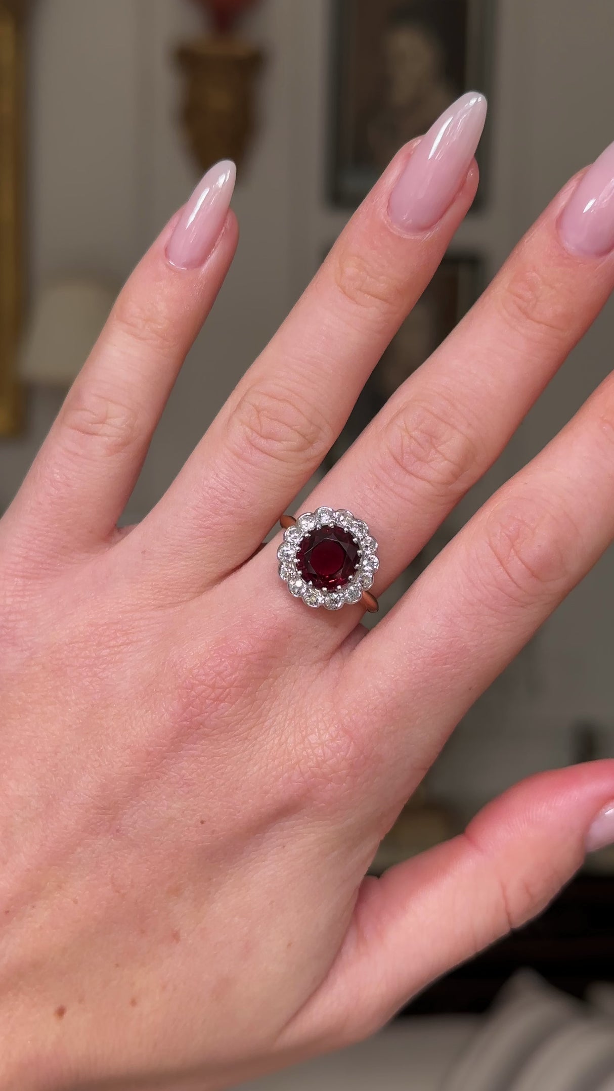 Edwardian garnet and diamond cluster ring, worn on hand and moved away from camera to give perspective.