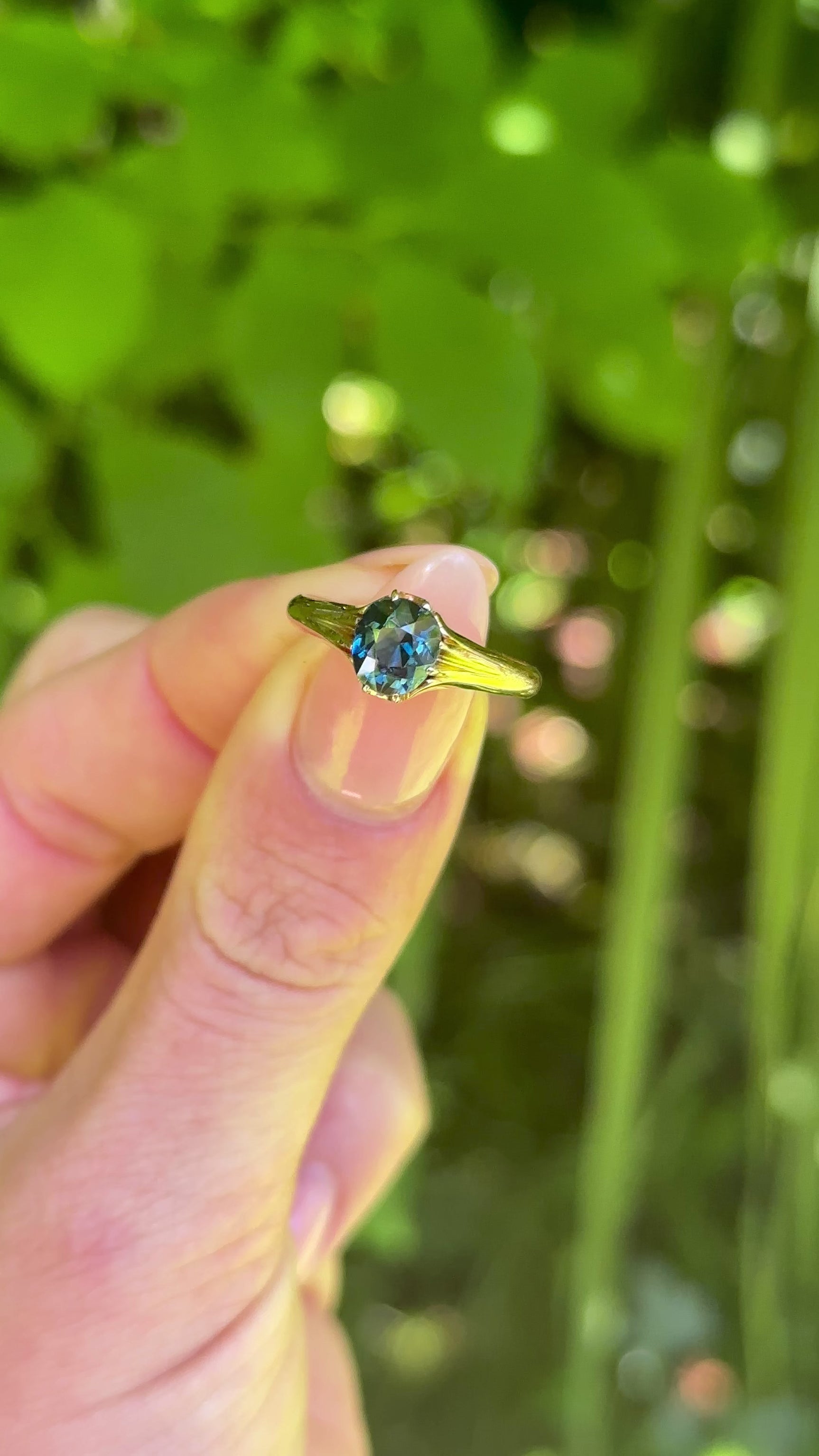 Antique, Edwardian Single-Stone Old Cut Teal Sapphire Ring, 18ct Rosy Yellow Gold held in fingers.