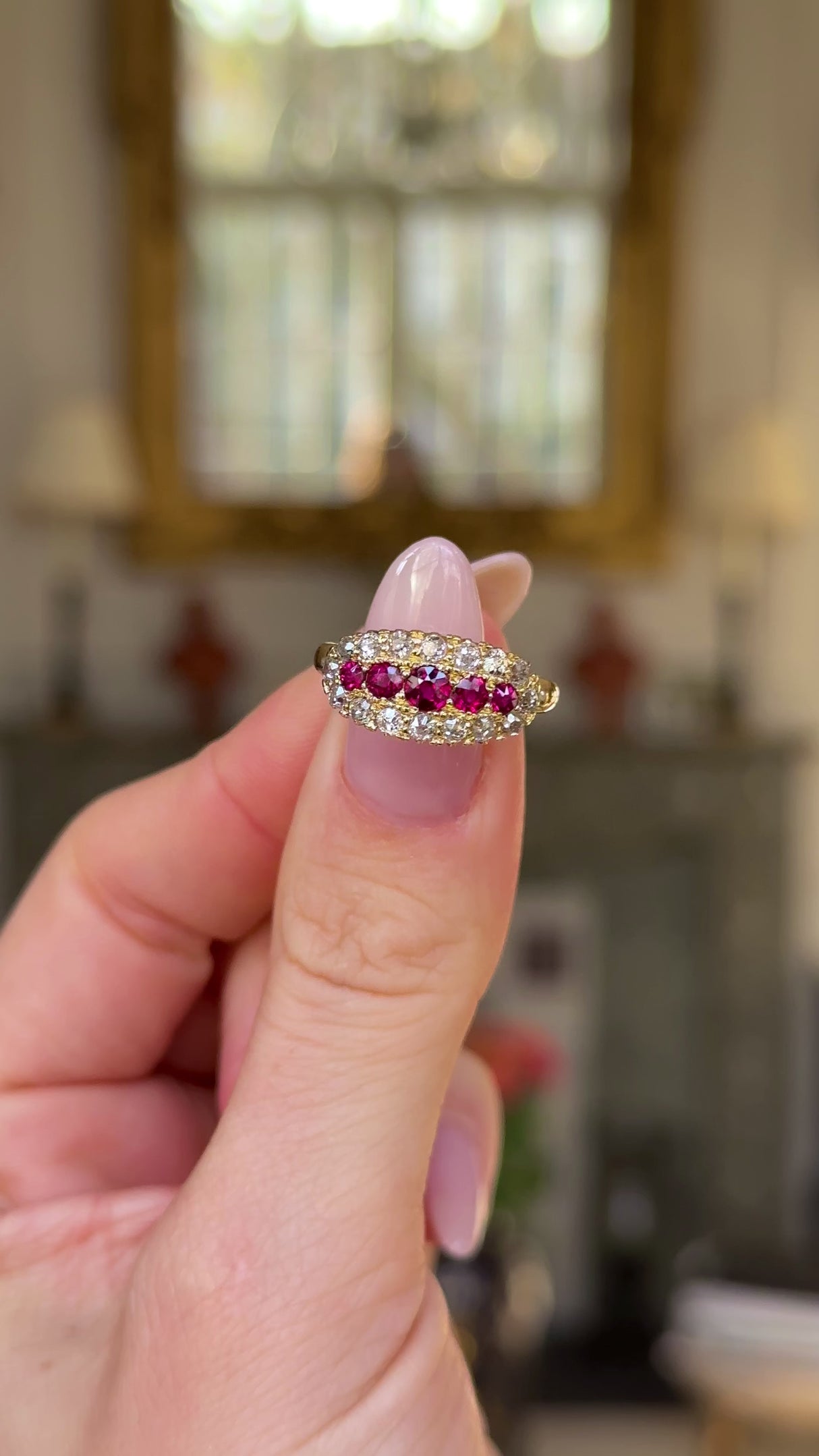 Ruby and diamond cluster engagement ring held in figners and moved around to give perspective.