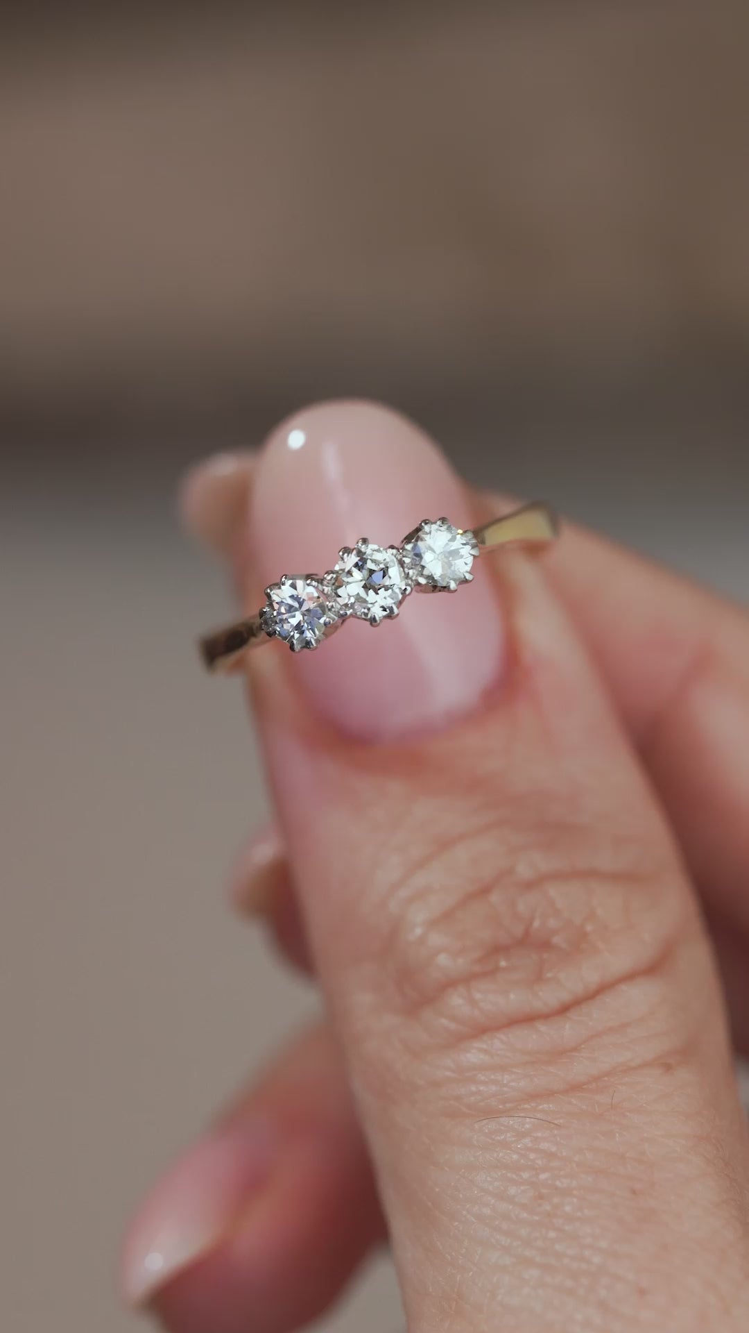 A close-up video of the antique diamond ring held between fingers, showcasing the old-cut diamonds and delicate claw settings.
