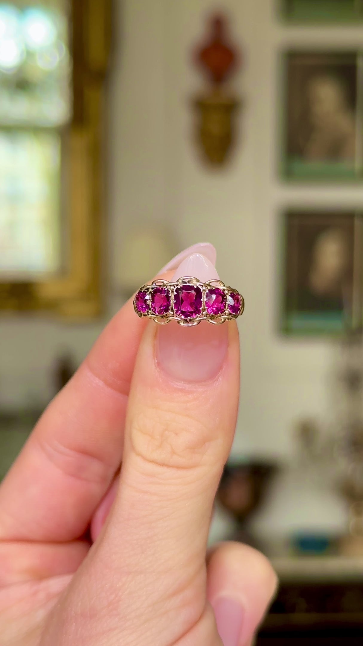 Victorian five-stone garnet and yellow gold ring, held in fingers and rotated to give perspective.