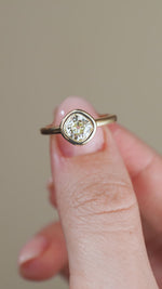A video showing the diamond solitaire held between fingers, revealing the beautiful old-cut faceting and simple, refined gold design.