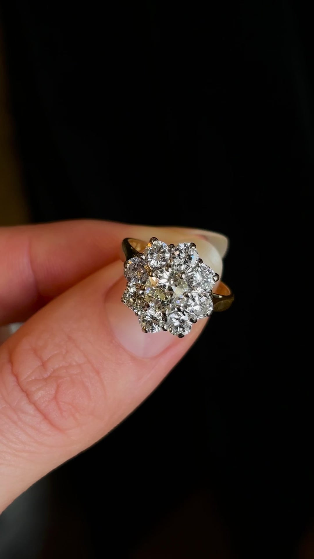 Vintage 1980s diamond cluster ring held in two fingers and rotated slowly to show fine details of the stones. 