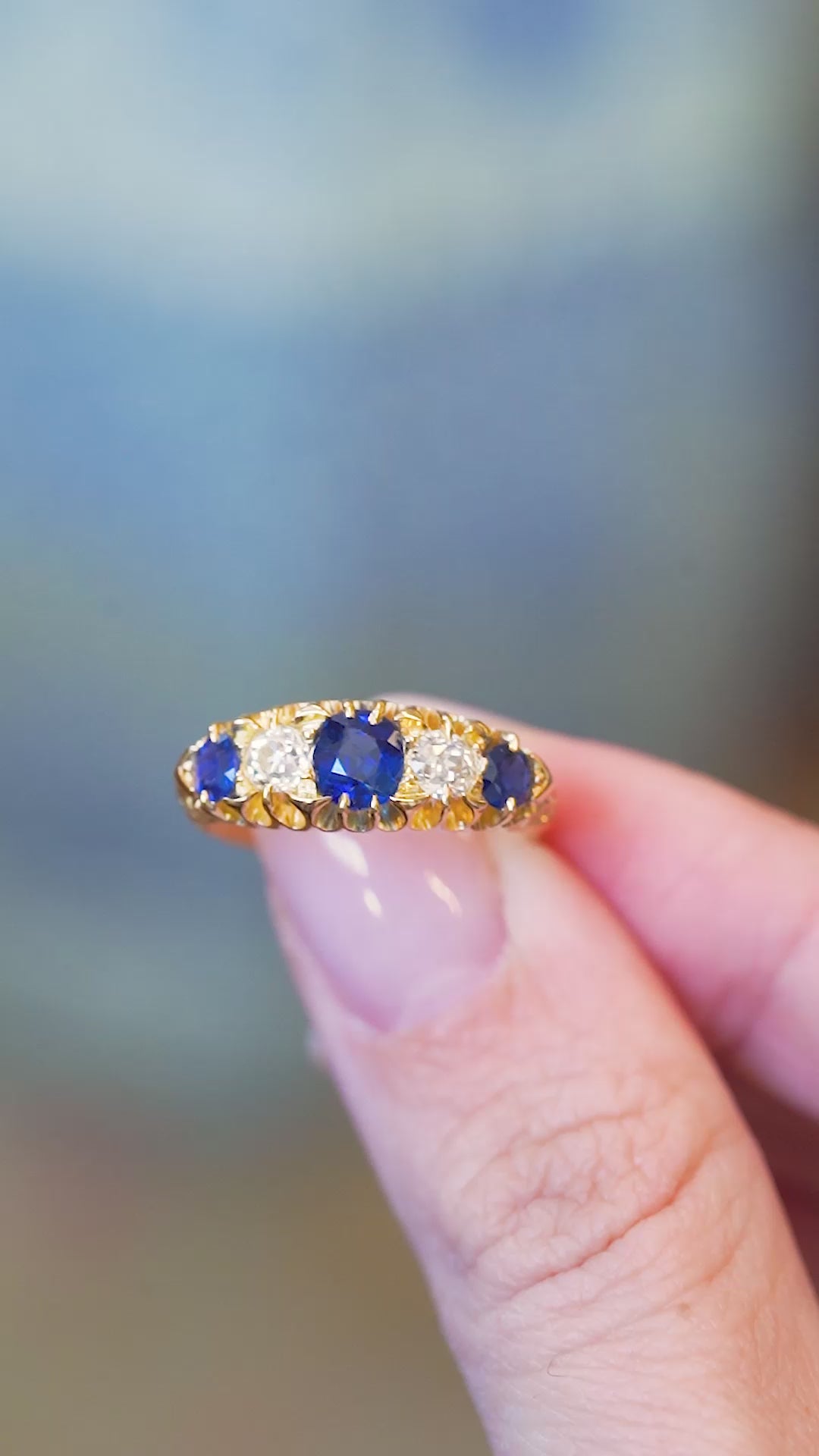 Sapphire and old mine cut diamond five stone ring shown in close detail with central blue stone.