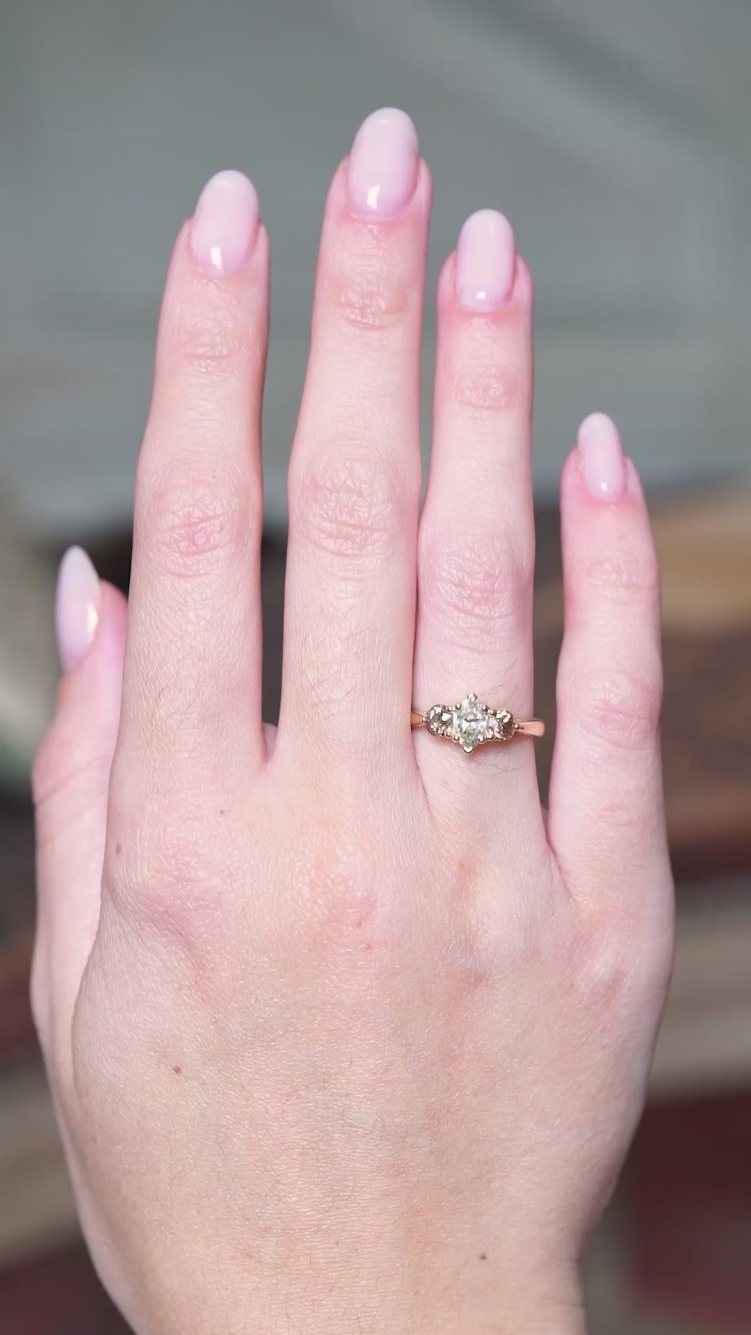 Diamond three-stone engagement ring with marquise-cut centre diamond worn on hand showing subtle movements.