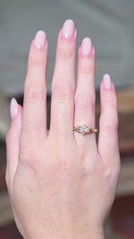 Diamond three-stone engagement ring with marquise-cut centre diamond worn on hand showing subtle movements.