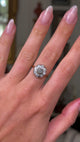 antique diamond daisy cluster engagement ring, worn on hand and moved away from camera to provide perspective. 