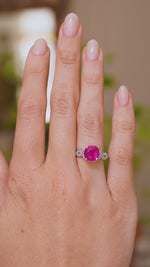 A video of an Antique, 1920s Art Deco pink ruby flanked solitaire engagement ring in white gold worn on a wedding finger and rotated to showcase the profiles and fit of the ring when worn. 