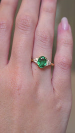 A video of a vintage-inspired oval-cut emerald and diamond trefoil engagement ring in yellow gold worn on the hand.