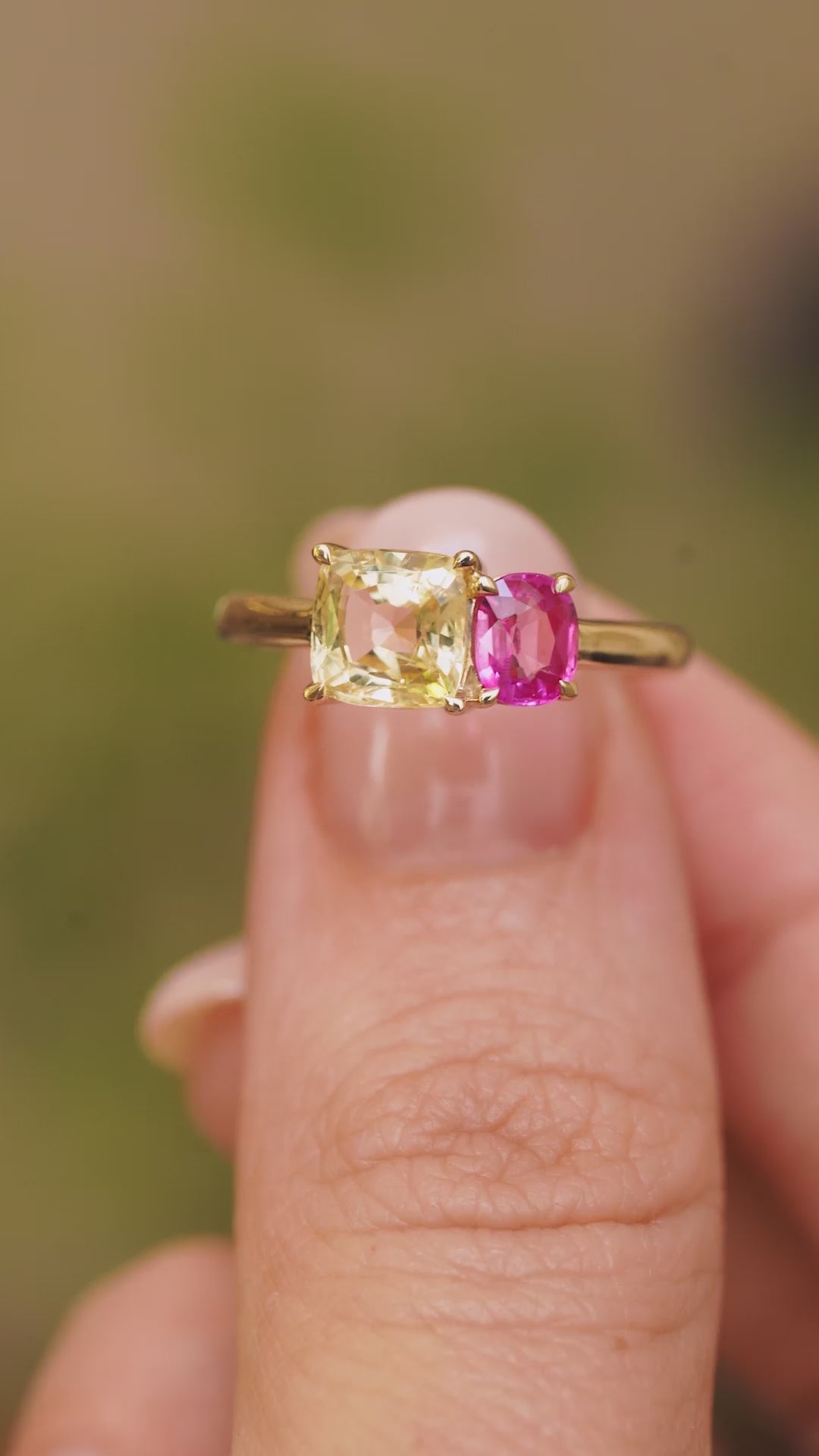 A video of an Antique-inspired, Yellow and pink sapphire Toi et Moi two stone engagement ring in yellow gold held between the fingers and rotated to show angles