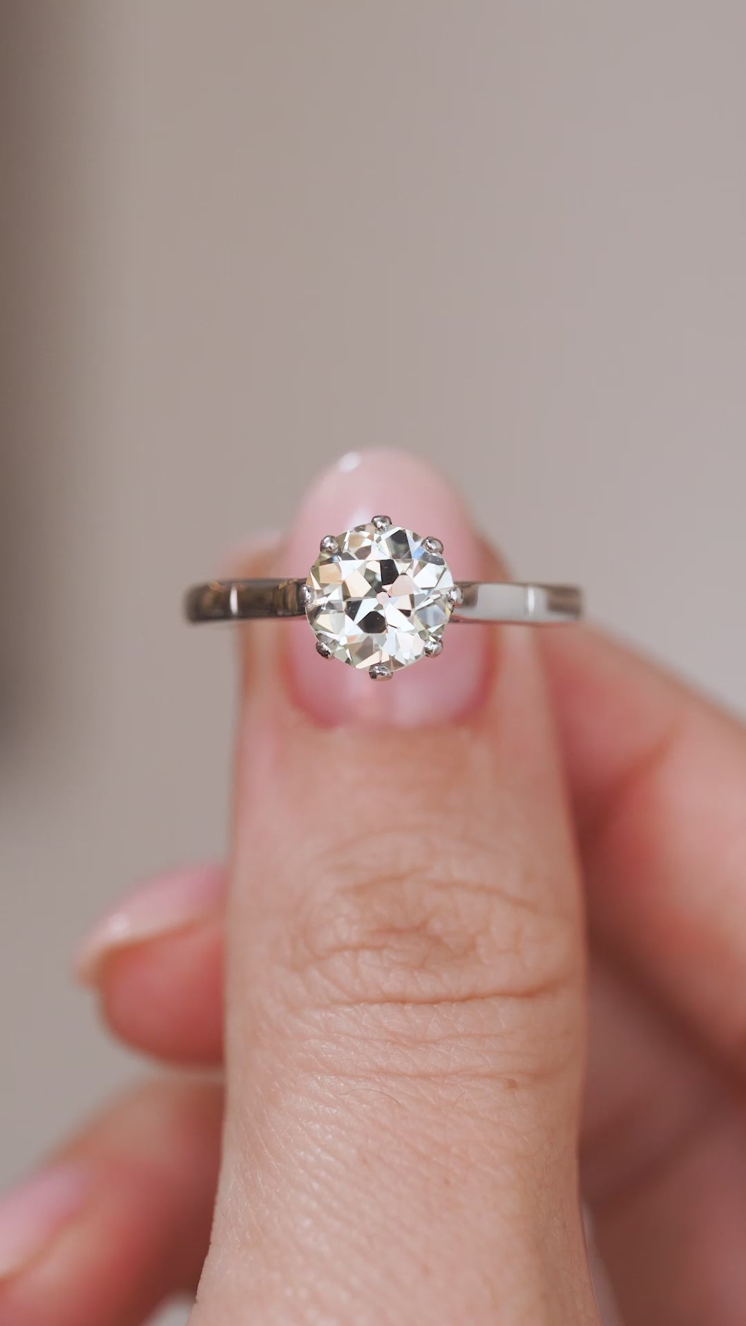 Video close-up of the antique diamond solitaire balanced on a fingertip, highlighting the platinum mount and centre stone.