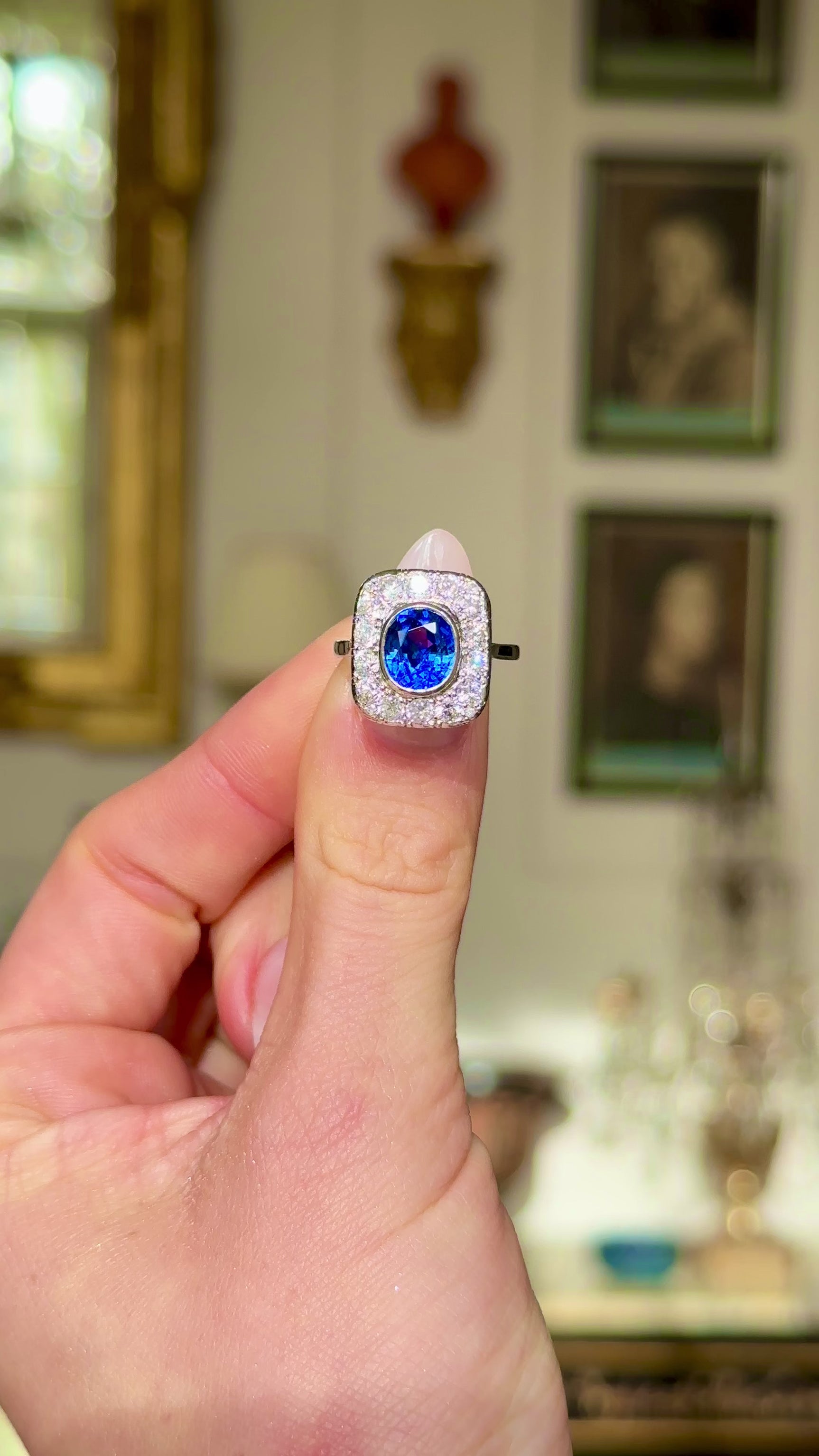 Art Deco sapphire and diamond cluster ring, held in fingers and moved around to give perspective.