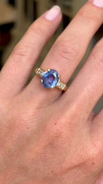 Vintage 1990s sapphire and diamond engagement ring featuring an oval blue sapphire centre stone with diamond-set shoulders, displayed on a hand.