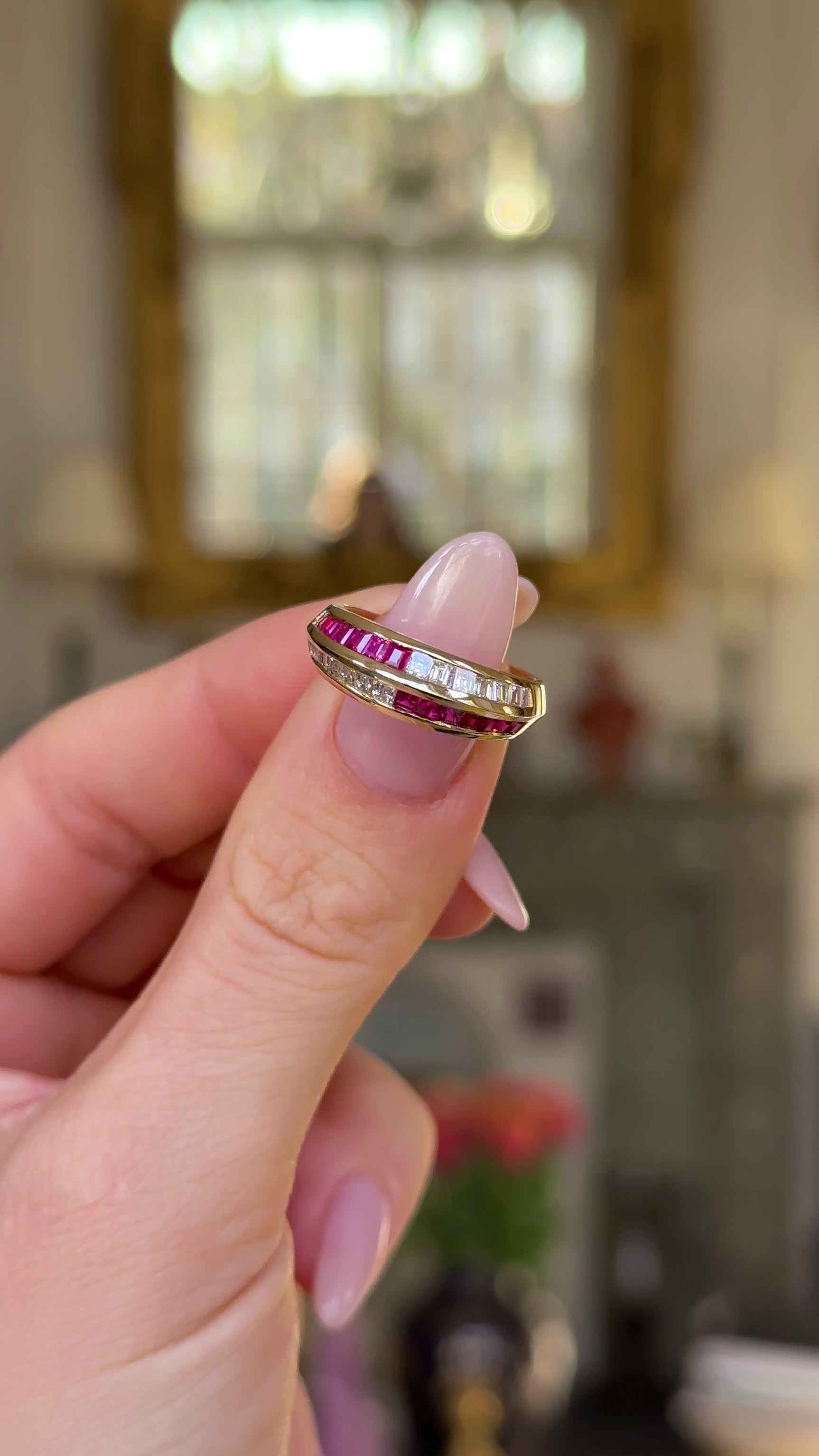 Ruby and diamond half eternity ring held in fingers and moved around to give perspective.