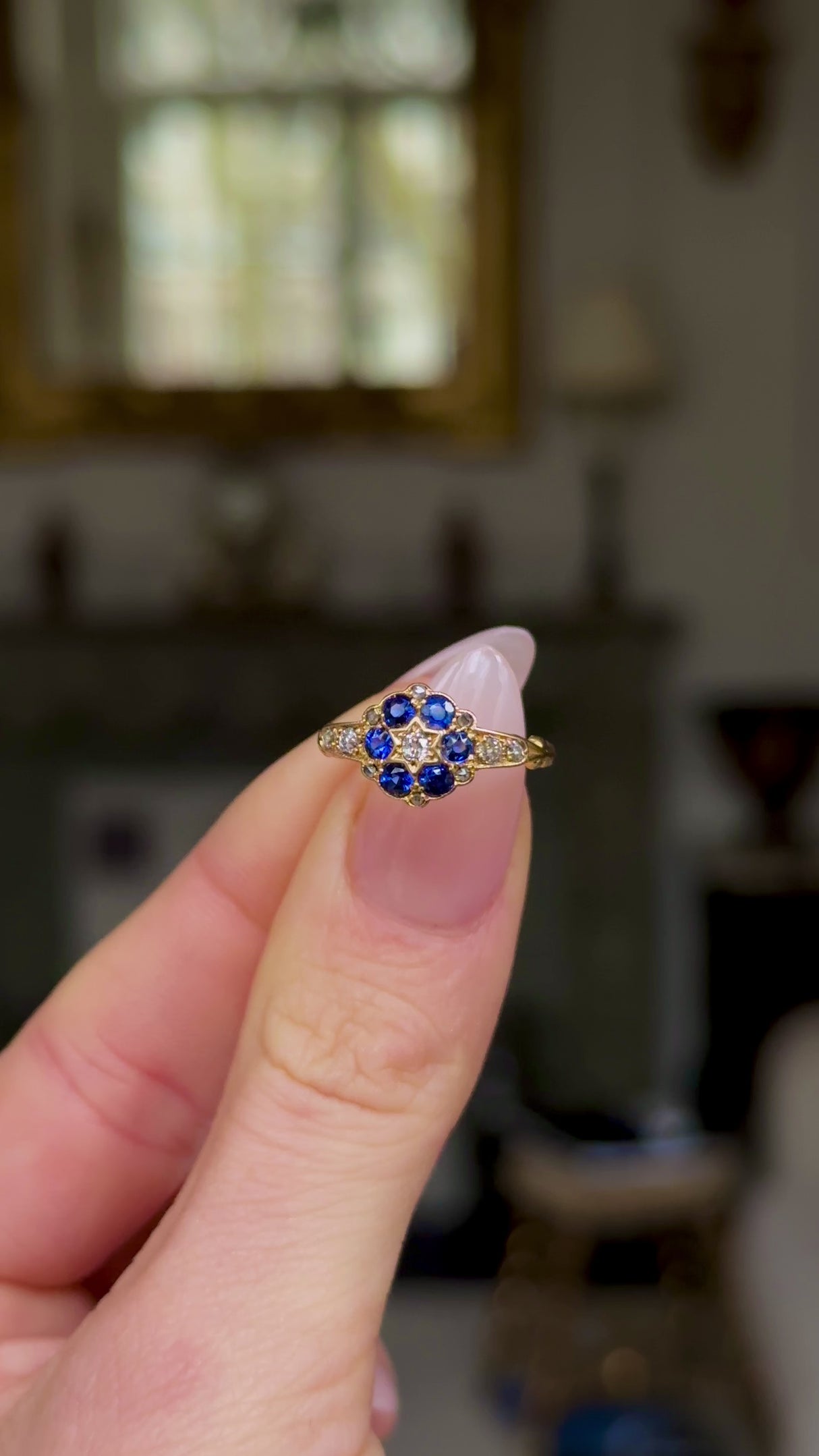 Antique, Edwardian Sapphire and Diamond Cluster Ring,  held in fingers and moved around to give perspective.