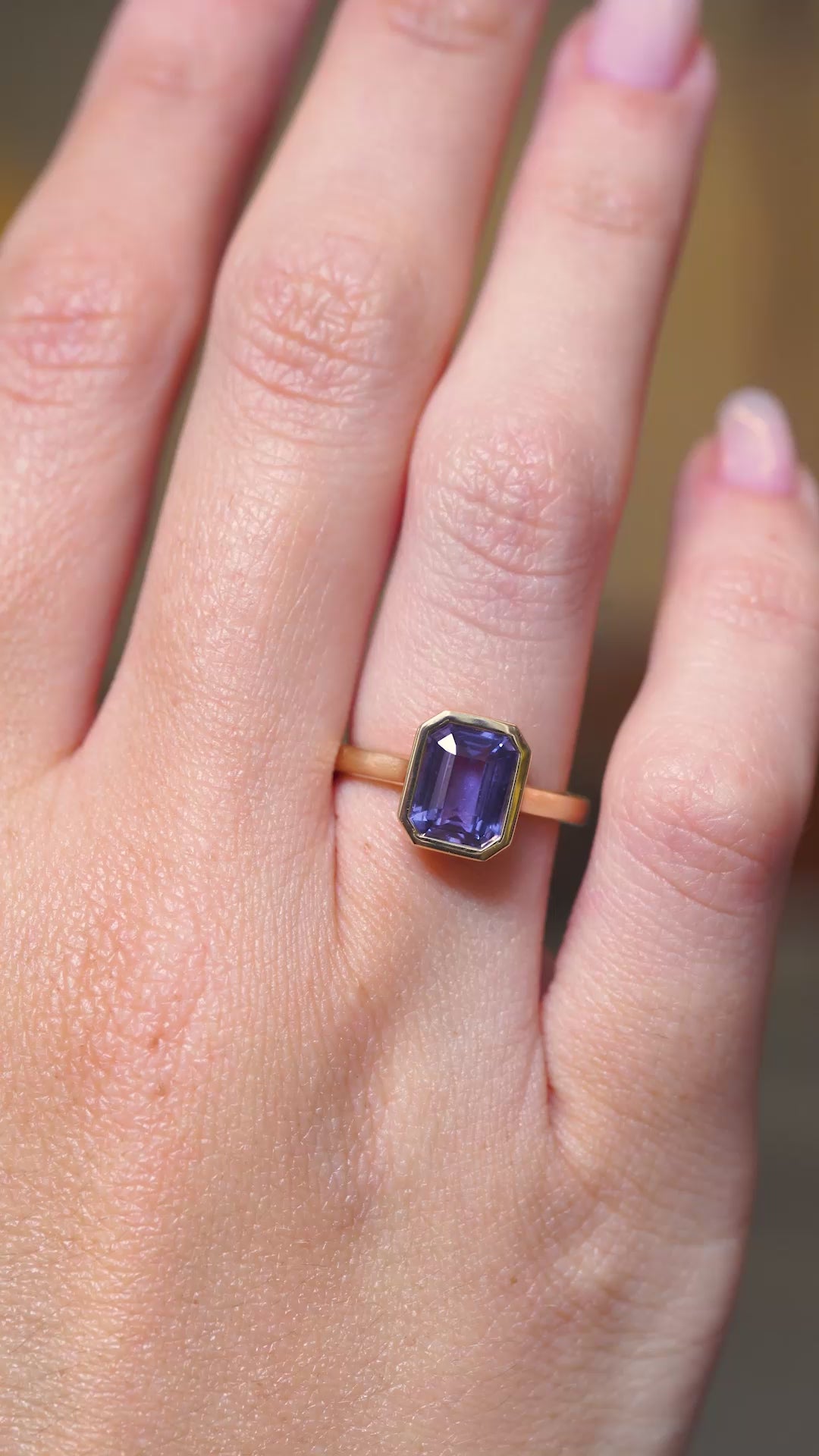 A video of an antique-inspired indigo blue sapphire solitaire engagement ring in yellow gold worn on a hand.