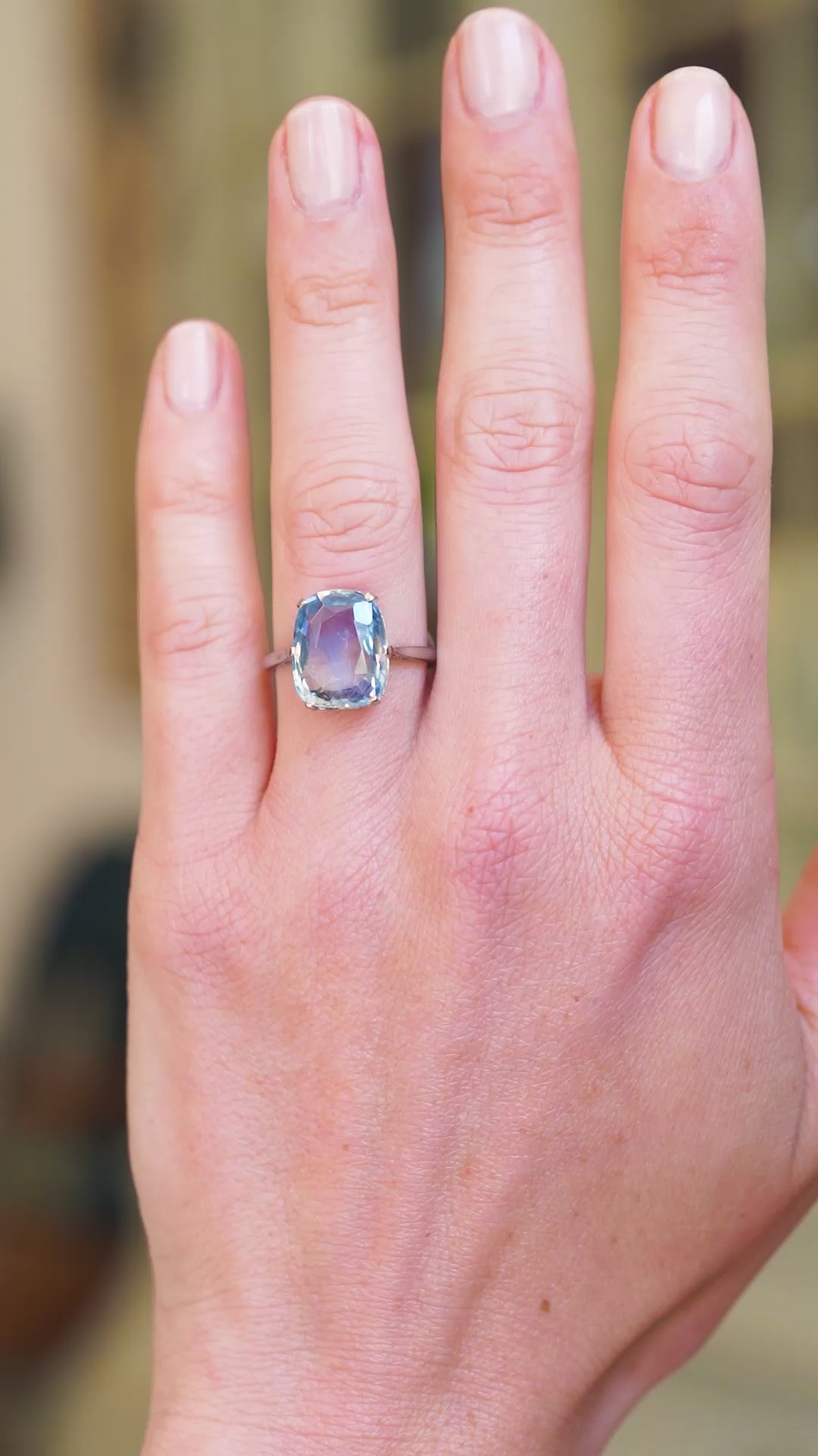 Solitaire ring worn on hand showing soft blue sapphire tone and natural movement.