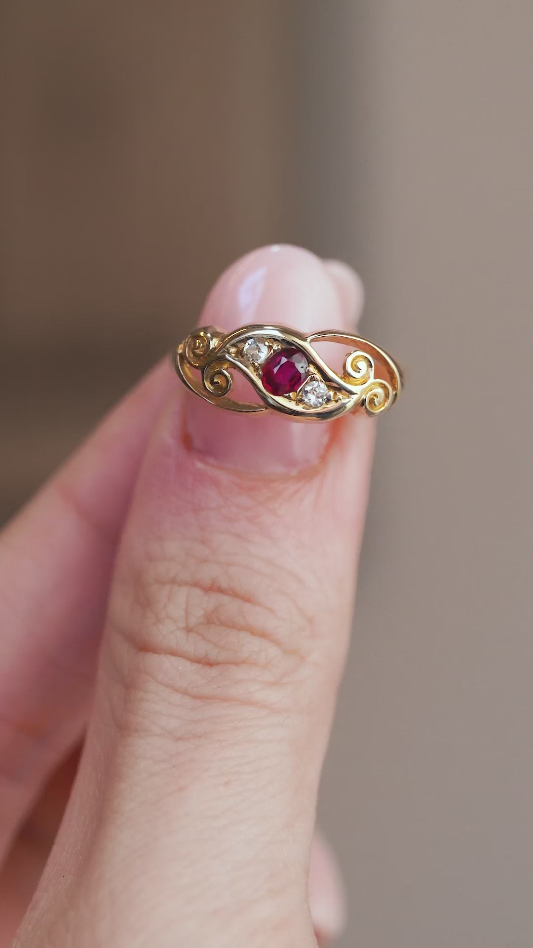 Video presenting the antique ruby and diamond ring balanced on a fingertip for a detailed view of its flowing openwork design.