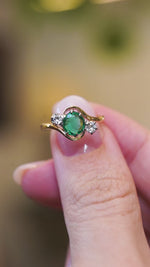 Emerald ring with diamond side stones showing light reflections and subtle sparkle.