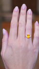 Orange cushion cut sapphire and diamond cluster trefoil ring worn on hand showing fit and natural movement.