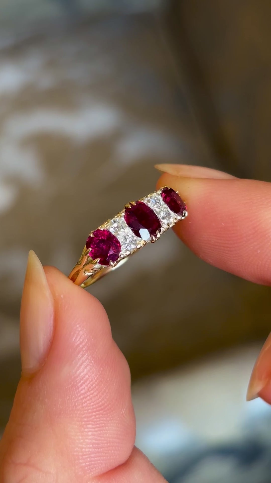 Antique, Victorian ruby and diamond three-stone ring held in fingers and rotated slowly to show fine details 