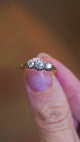 Three stone diamond ring worn on hand with subtle movement and natural light reflections.