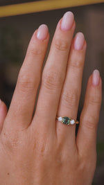 A video of an Antique-inspired, Teal sapphire and diamond three-stone engagement ring worn on the hand and turned to show different angles