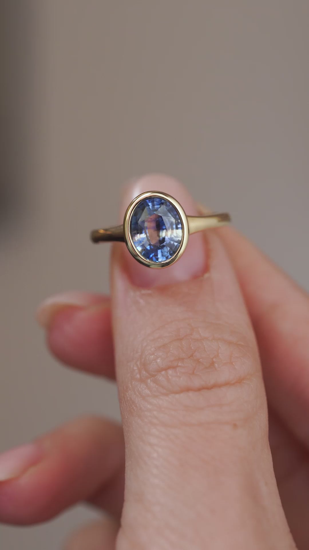 Video presenting the antique-inspired sapphire engagement ring balanced on a fingertip as the faceted blue stone catches the light.