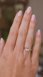 A close up video of a Vintage-inspired solitaire ring worn on a wedding finger and rotated slowly to display the yellow gold band, side profile of the bezel setting and the round pink Sri Lankan sapphire.