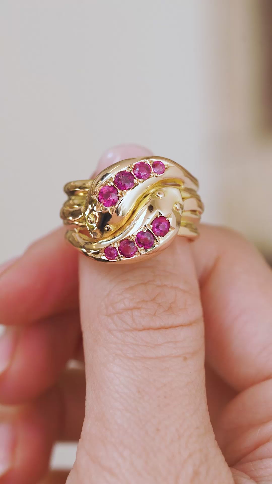 Video close-up of the antique ruby snake ring balanced on a fingertip, displaying its ornate carved gold design.