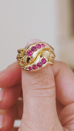 Video close-up of the antique ruby snake ring balanced on a fingertip, displaying its ornate carved gold design.
