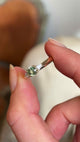 Side profile of round green sapphire and diamond three-stone engagement ring in yellow gold setting.
