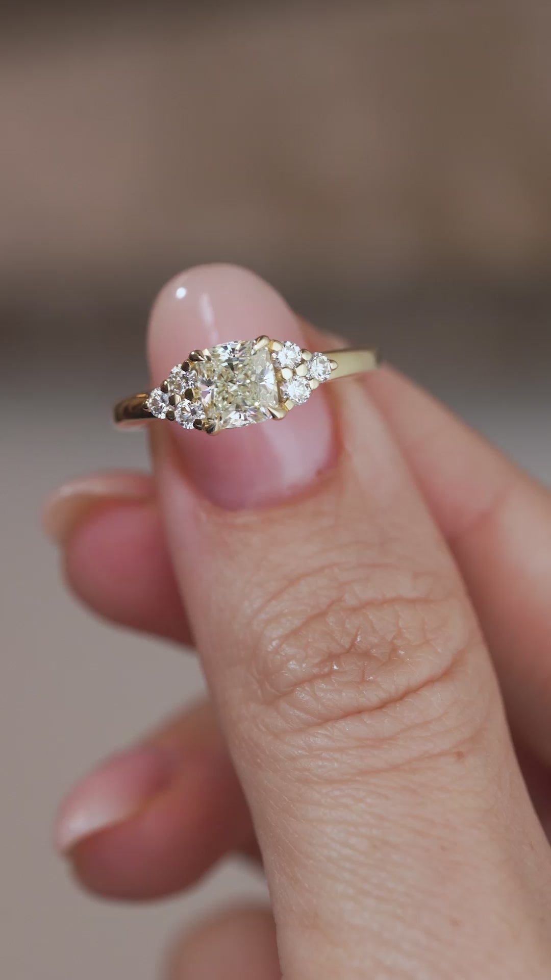 A close-up video of the yellow gold diamond ring held between fingers, showcasing its intricate trefoil design and diamond sparkle.