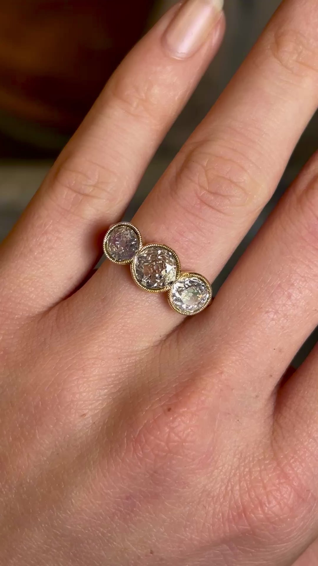 Antique, Victorian three-stone diamond ring worn on hand and moved back to show size of ring on hand. 
