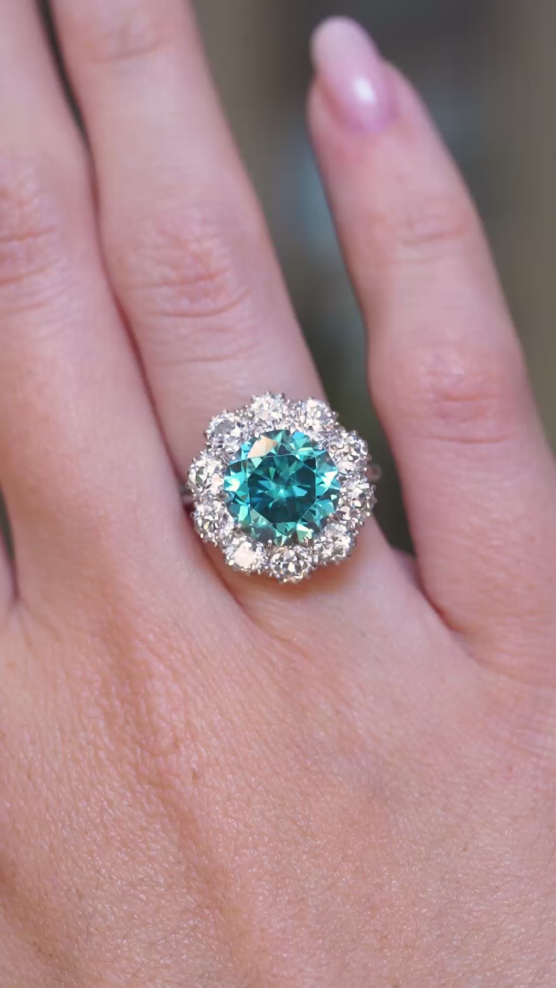 A video of an antique Edwardian zircon and diamond halo cluster cocktail ring shown on a hand.