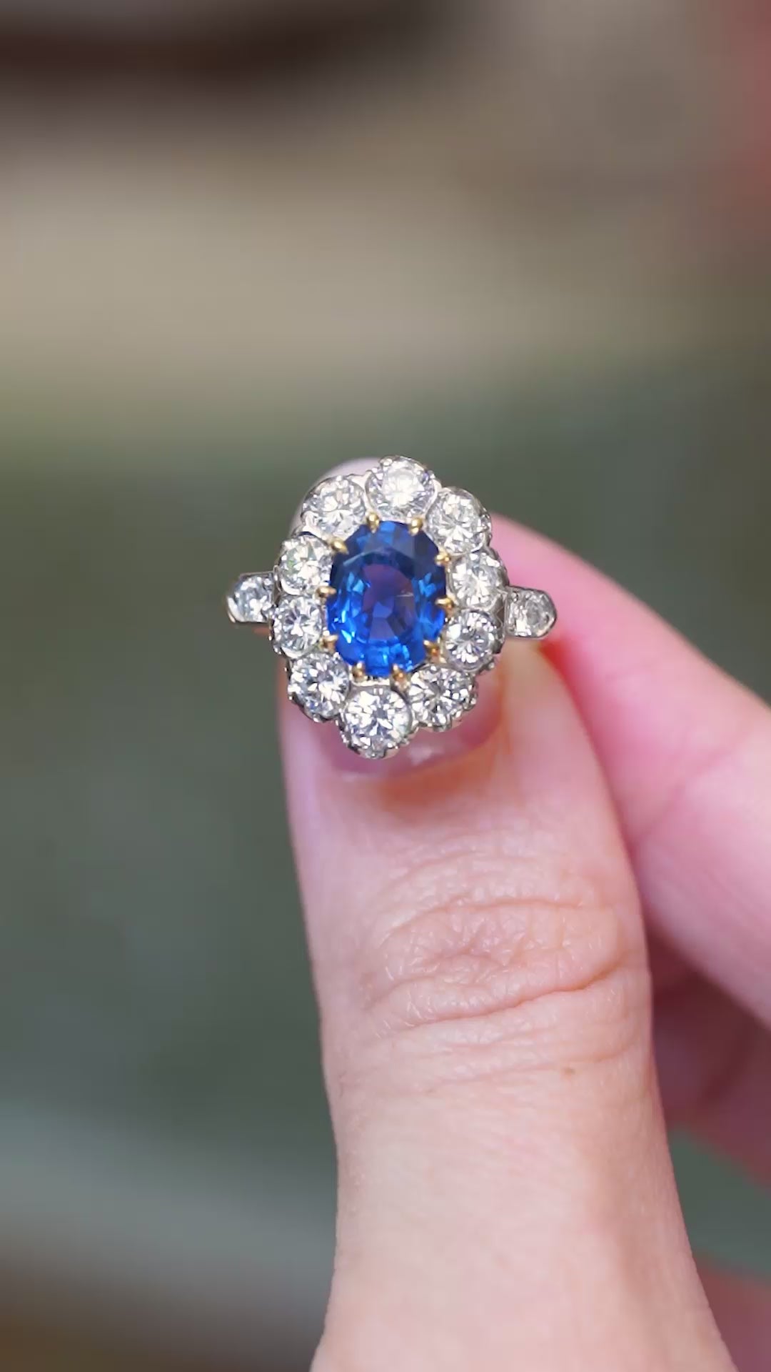 Vintage 1960s French sapphire and diamond cluster ring shown in movement between fingers.