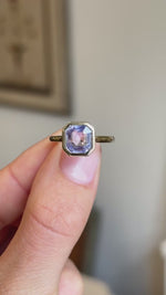 Close-up video of an antique-inspired yellow gold sapphire solitaire ring showcasing a square lavender sapphire in a polished rub-over setting, highlighting its pastel lilac colour, brilliance and refined craftsmanship.