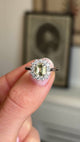 Close up video of a platinum Antique inspired, yellow sapphire and diamond cluster engagement ring held between two fingers and rotated slowly to show it's profile