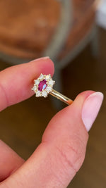 Close-up video of an antique-inspired yellow gold cluster ring showcasing an oval-cut ruby framed by sparkling diamonds, highlighting rich colour, brilliance and fine craftsmanship.