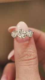 A video of a platinum and yellow gold Antique, Edwardian old-cut diamond three-stone engagement ring held between the fingers and rotated and turned to show off different angles and the profile