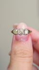 A video of an Antique three-stone diamond engagement ring held between the fingers and turned to show angles.