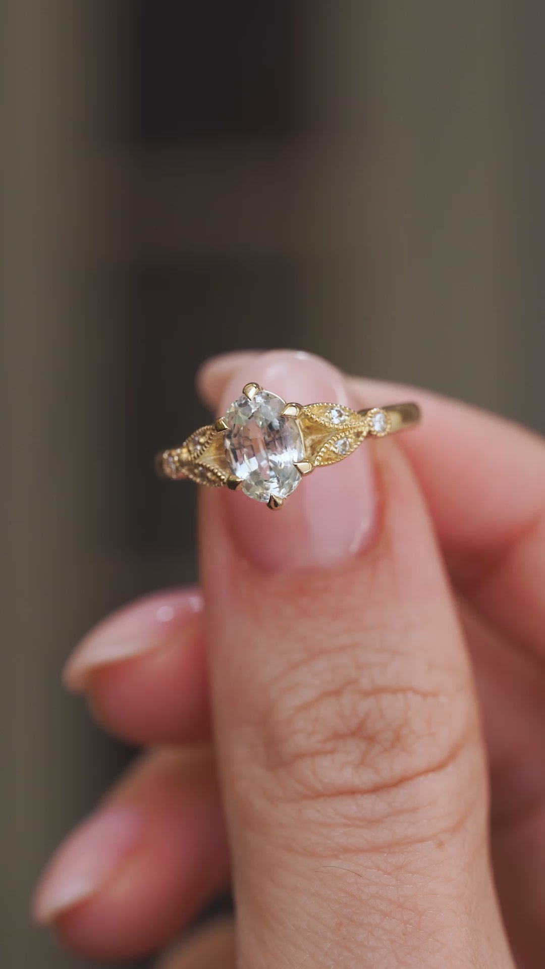 Video close-up of the vintage-inspired ring balanced on a fingertip, highlighting its gemstone and decorative gold work.