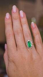 A video of a hand wearing an Antique, Belle Époque emerald and diamond cluster engagement ring.  Rotated slowly to show the profile of the ring once worn and the yellow gold band.  