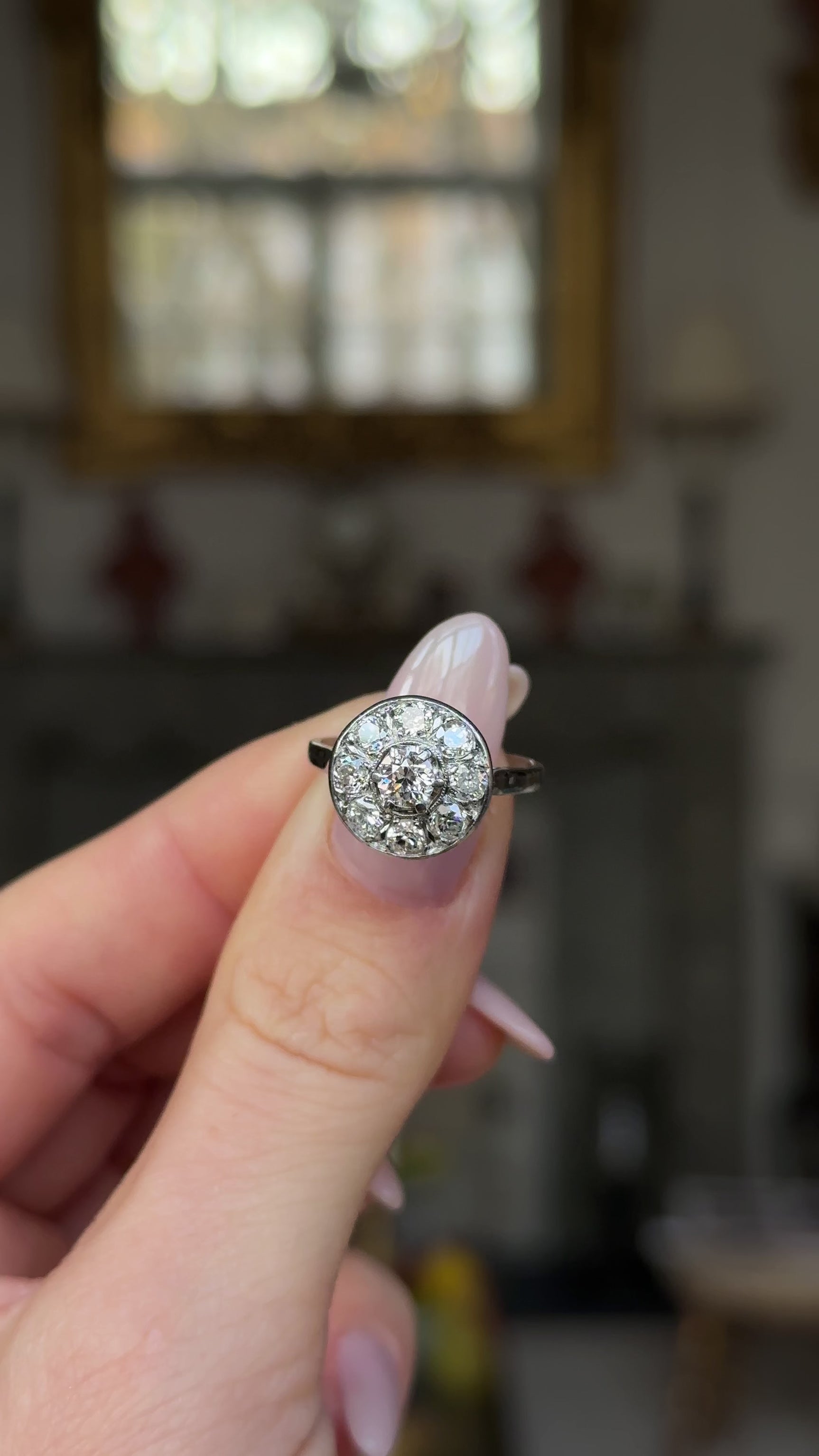 Art deco  diamond cluster ring held in fingers and moved around to give perspective.