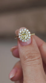 A close-up video of the yellow diamond engagement ring held between fingers, capturing the sparkle of the central diamond and surrounding halo.